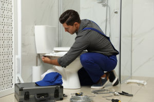 after hours plumber working on a bathroom toilet