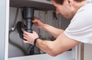 Plumber fixing a pipe under a sink